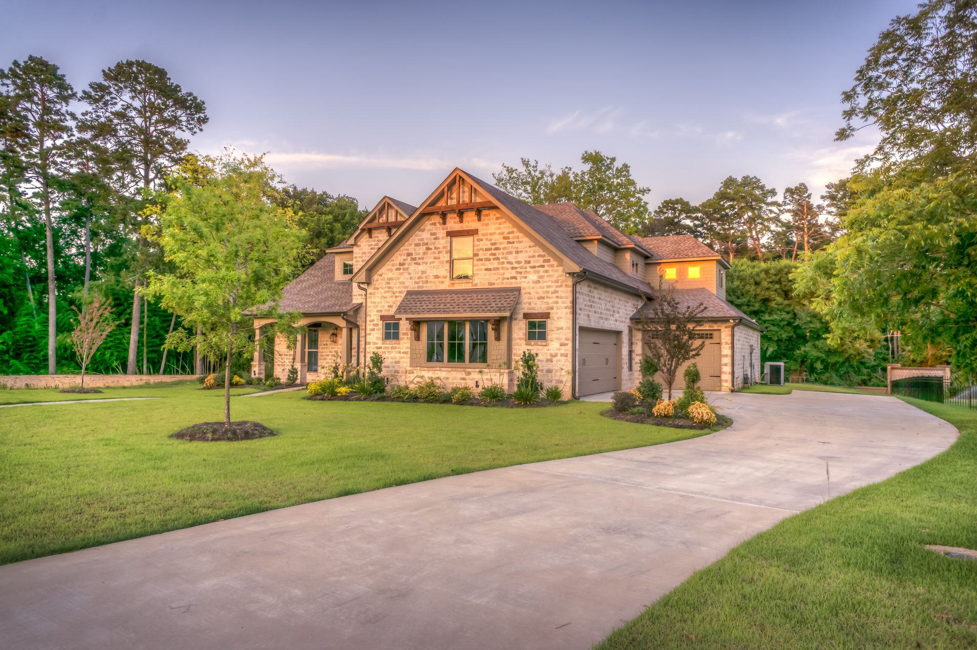 Stone home with a concrete driveway and landscaped front yard